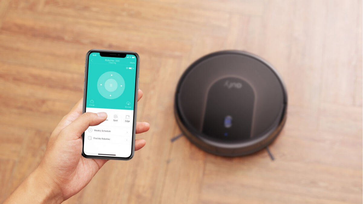 Seseorang sedang mengontrol robot vacuum cleaner melalui smartphone